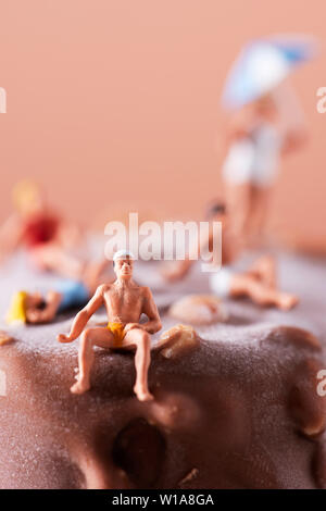 Primo piano della miniatura alcune persone che indossano il costume da bagno rilassante per un gelato al cioccolato bar Foto Stock