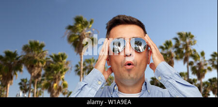 Sorpreso uomo in occhiali da sole su palme Foto Stock