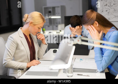 Il team di business con computer portatile lavora fino a tardi in ufficio Foto Stock