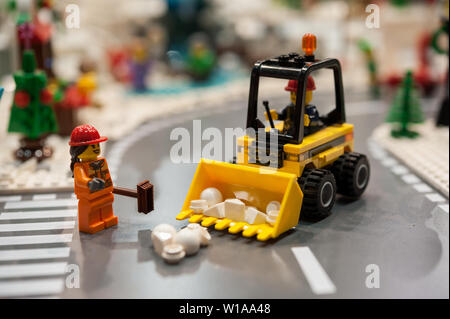 Dettaglio di mattoni in plastica modello con bulldozer e operai stradali. Gli uomini al lavoro in una strada della citta'. Foto Stock