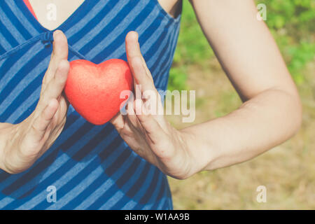 La gente, la relazione e il concetto di amore - womans mani cuore rosso su sfondo verde Foto Stock