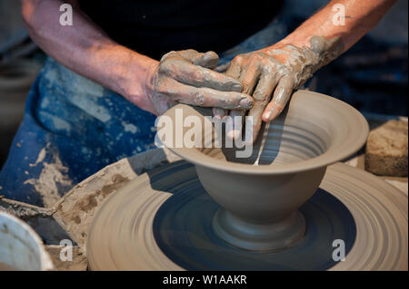 Potter a lavorare sulla ruota di ceramiche (close up mani e argilla grigia) Foto Stock