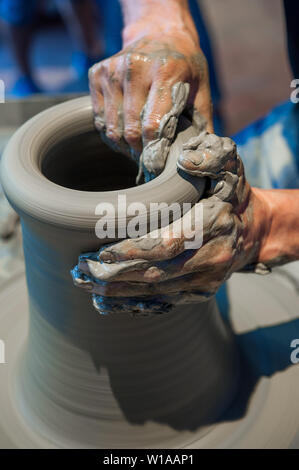 Potter a lavorare sulla ruota di ceramiche (close up mani e argilla grigia) Foto Stock