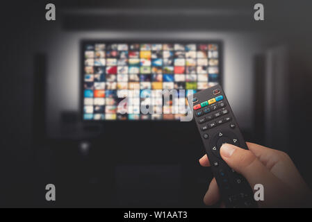 Multimedia concetto video sul televisore in camera oscura. L'uomo a guardare la TV con telecomando in mano. Foto Stock