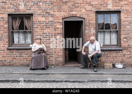 Due persone vestite con abiti eduardiano al di fuori di una casa a schiera, Black Country Living Museum, Dudley Regno Unito Foto Stock