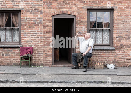 Vecchio Uomo seduto all'esterno di una casa a schiera, Black Country Living Museum, Dudley Regno Unito Foto Stock