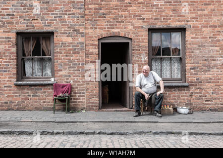 Vecchio Uomo seduto all'esterno di una casa a schiera, Black Country Living Museum, Dudley Regno Unito Foto Stock