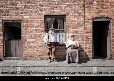 Due persone vestite con abiti eduardiano al di fuori di una casa a schiera, Black Country Living Museum, Dudley Regno Unito Foto Stock