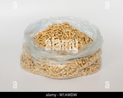 Pellet di legno in una plastica sacchetto di cellophane su sfondo bianco. Biocarburanti alternativi da segatura per la combustione nei forni e fornelli. Lettiera di gatto. Foto Stock