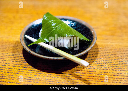 Sakuramochi wagashi dolce giapponese consistente di colore rosa torta di riso con pasta di fagiolo rossa avvolto in un decapato cherry blossom leaf Foto Stock