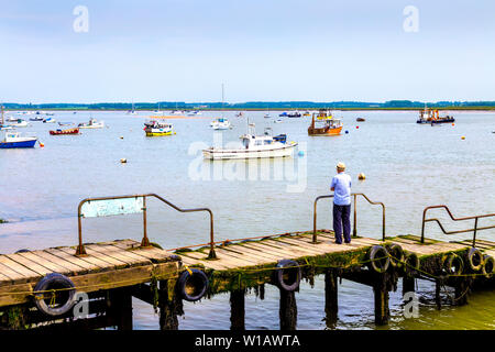 Uomo anziano in piedi su un molo vicino a Felixstowe Ferry Boat Yard, Suffolk, Regno Unito Foto Stock
