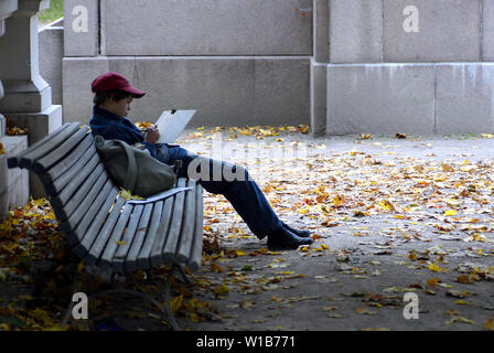 Il ragazzo è seduto su una panchina nel parco e il disegno Foto Stock