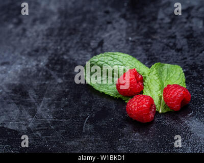 Vista dall'alto di un frullato di lamponi set di vetro su assi di legno e decorato con cannuccia, tre lamponi e foglie di menta. Messa a fuoco selettiva. Foto Stock