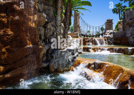 Cascate e ponte oscillante nei motivi del Mandalay Bay Resort & Casino vista attraverso un arco, Las Vegas, Nevada, STATI UNITI D'AMERICA Foto Stock