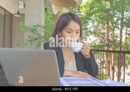 Imprenditrice di bere il caffè e la lettura del documento finanziario relazioni Foto Stock