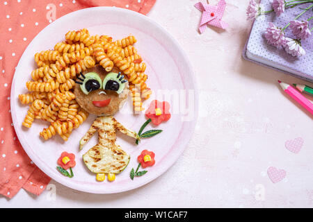 Funny Girl cibo faccia con cotoletta, pasta e verdure Foto Stock