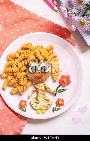 Funny Girl cibo faccia con cotoletta, pasta e verdure Foto Stock