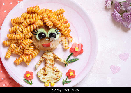 Funny Girl cibo faccia con cotoletta, pasta e verdure Foto Stock