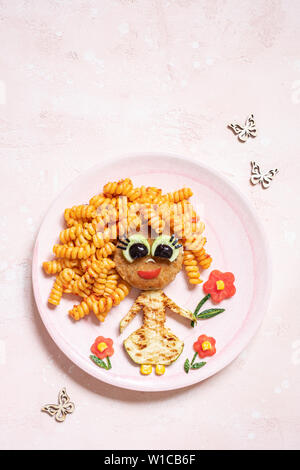 Funny Girl cibo faccia con cotoletta, pasta e verdure Foto Stock