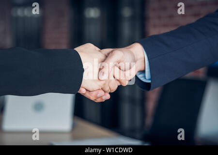 Chiudere la stretta di mano tra imprenditrice e imprenditore a sala riunioni in ufficio moderno Foto Stock