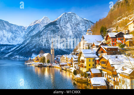 Classic vista da cartolina famosa Hallstatt Lakeside Town nelle Alpi con tradizionale nave passeggeri su una bella fredda giornata soleggiata con cielo blu e nuvole in inverno, Austria Foto Stock