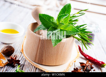 Erbe aromatiche. Fresco verde organico alle erbe aromatiche foglie in mortaio di legno Foto Stock