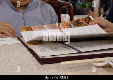 Movimento della donna che guarda all'interno del menu di un ristorante cinese Foto Stock