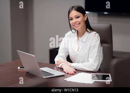 Bella giovane imprenditrice utilizzando laptop in sala conferenze Foto Stock