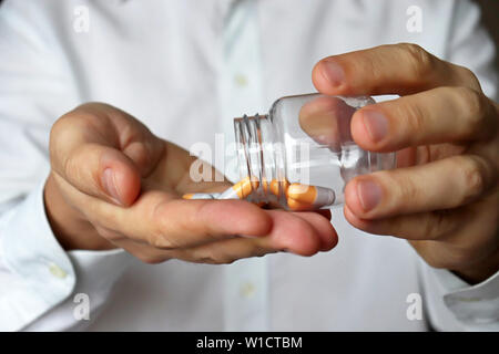 Medico con una bottiglia di pillole, terapeuta dando farmaco in capsule. Concetto di dose di farmaci, vitamine, prescrizione medica, farmacia Foto Stock