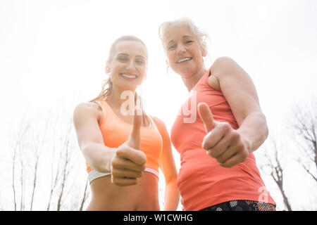 Donna Senior e figlia dando Pollice su per lo sport Foto Stock