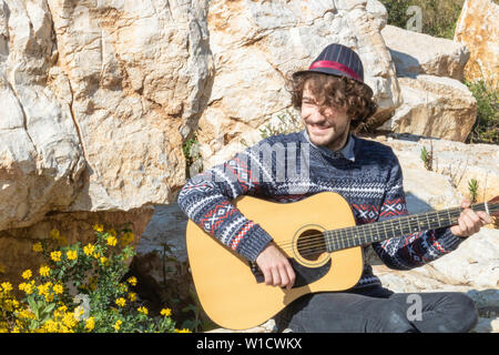 Giovane uomo suonare la chitarra acustica all'aperto Foto Stock