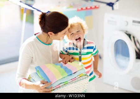 Madre e bambini in lavanderia con lavatrice o asciugatrice. Le