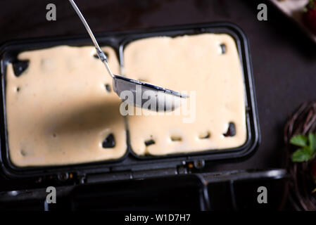 Waffle impasto versando sulla macchina di cottura close up Foto Stock