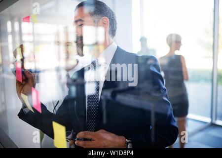 Lavoro di squadra creativa nella parte anteriore della parete di vetro utilizzando post-it e adesivi Foto Stock