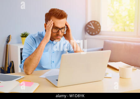 Preoccupato uomo letto lettura notizie sul suo computer portatile Foto Stock