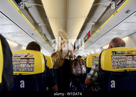 Una bionda dai capelli donna passeggero con sacchi sul volo Ryanair Foto Stock