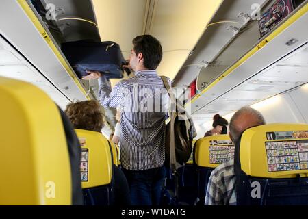 Un uomo mette il suo sacchetto in un armadietto sopraelevato su un volo Ryanair Foto Stock