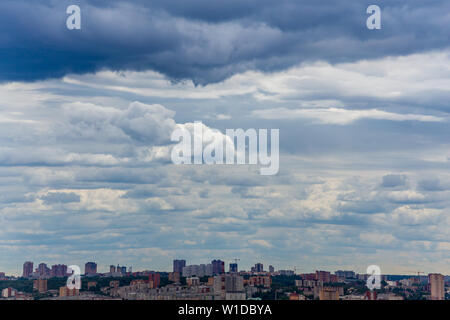 Estate russa daylight cityscape con grandi cumuli di nuvole e la piccola linea di orizzonte del pannello case di condominio. Foto Stock