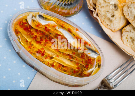 Conserve di sardine marinate con spezie in contenitore di plastica Foto Stock