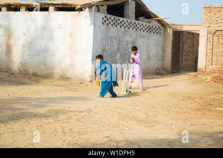 Rahimyar khan,punjab,pakistan-luglio 1,2019:alcuni ragazzi locali a giocare a cricket in un villaggio.battitore giocando un colpo. Foto Stock