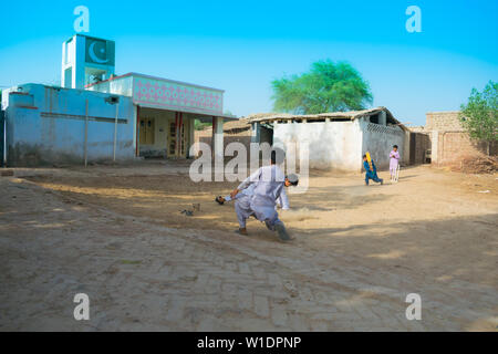 Rahimyar khan,punjab,pakistan-luglio 1,2019:alcuni ragazzi locali a giocare a cricket in un villaggio,fielder sta cercando di catturare la sfera. Foto Stock