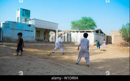 Rahimyar khan,punjab,pakistan-luglio 1,2019:alcuni ragazzi locali a giocare a cricket in un villaggio,battitore giocando un colpo,polvere battenti. Foto Stock