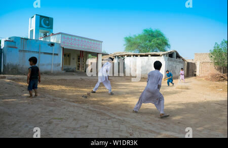 Rahimyar khan,punjab,pakistan-luglio 1,2019:alcuni ragazzi locali a giocare a cricket in un villaggio,battitore giocando un colpo,polvere battenti. Foto Stock