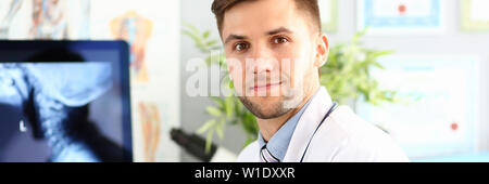 Sorridente medico maschio lavora con calcolo nel suo ufficio Foto Stock