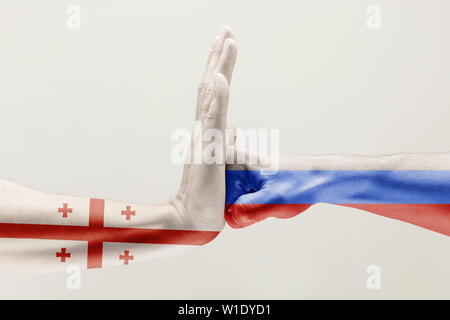 Pressione di arresto. Due mani maschio combattimenti colorati nella Federazione di Russia e Georgia bandiere isolato su bianco di sfondo per studio. Concetto di politico, economico, sociale aggressioni, disaccordo. Foto Stock