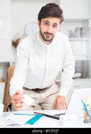 Amichevole maschio giovane lavoratore di ufficio consegna business card in ufficio Foto Stock