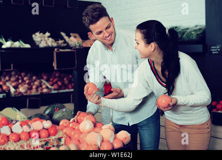 Famiglia sorridente esaminando vari frutti nel negozio di alimentari Foto Stock