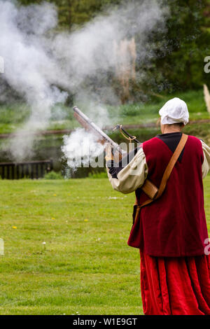 Donna in costume medievale a dimostrazione di una arma da fuoco antica Foto Stock