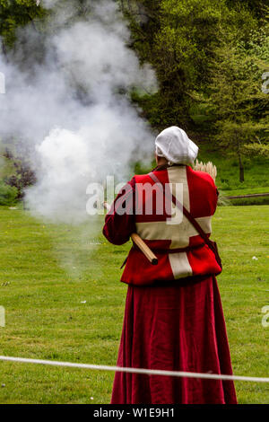 Donna in costume medievale a dimostrazione di una arma da fuoco antica Foto Stock