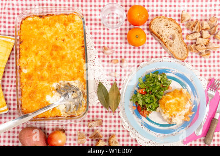 Baccalà con panna, un tradizionale piatto portoghese, con patate, cipolle, olio di oliva e ricoperto con formaggio parmigiano, cotta in forno. Foto Stock